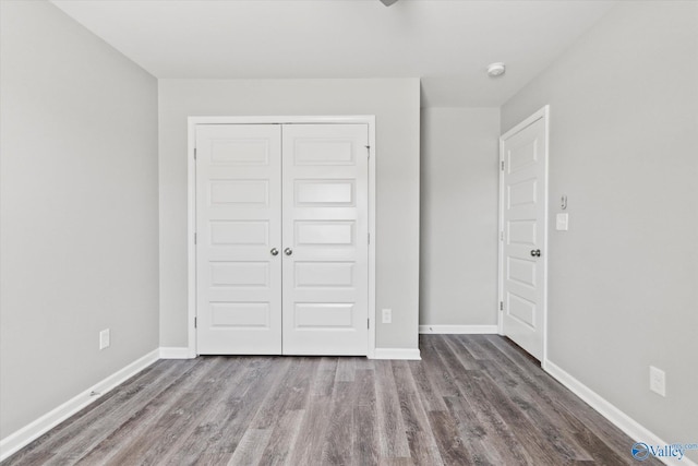 unfurnished bedroom with a closet, baseboards, and wood finished floors