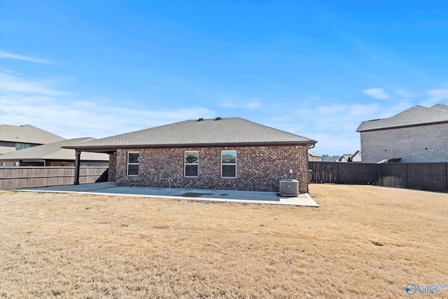 rear view of property with a patio, central AC unit, a fenced backyard, brick siding, and a yard