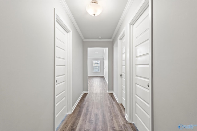 hallway with baseboards, wood finished floors, and crown molding