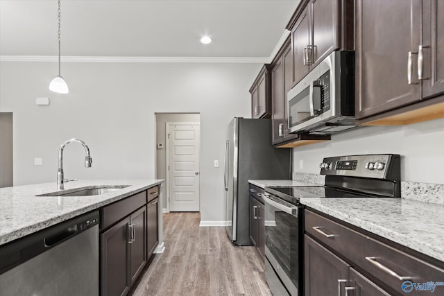 kitchen featuring light stone counters, decorative light fixtures, crown molding, stainless steel appliances, and a sink