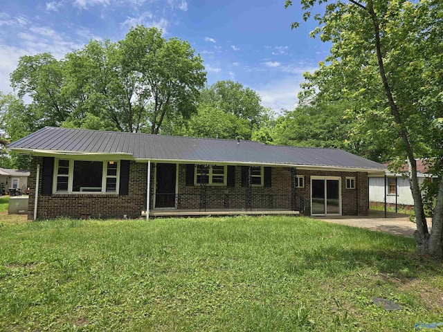 ranch-style house with brick siding, metal roof, a front lawn, and a patio area