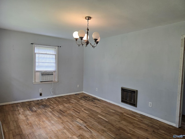 empty room featuring a chandelier, wood finished floors, cooling unit, and baseboards