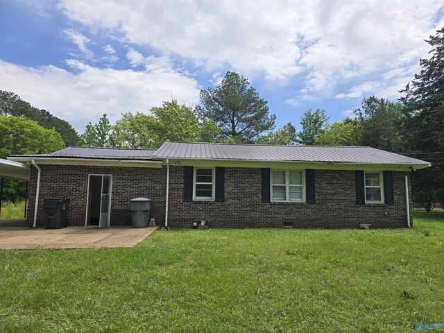 back of property with a yard, metal roof, a patio, and brick siding
