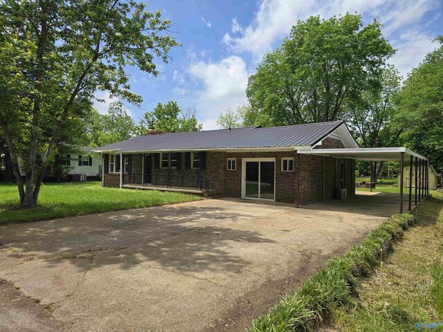 single story home featuring brick siding, driveway, a front lawn, metal roof, and an attached carport