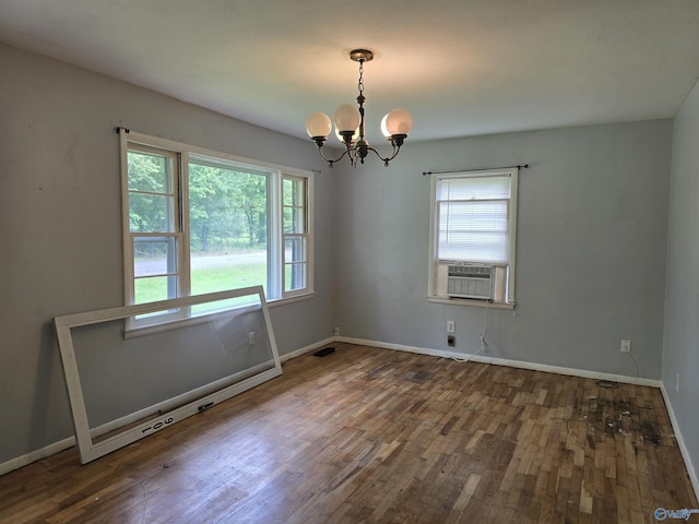 spare room featuring a chandelier, wood finished floors, baseboards, and cooling unit