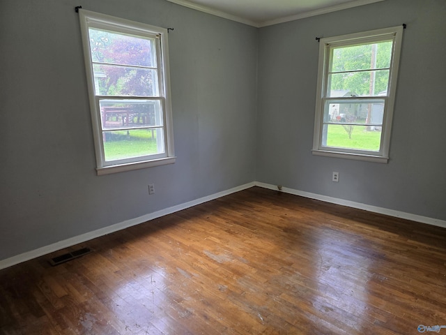 spare room with crown molding, healthy amount of natural light, hardwood / wood-style floors, and baseboards