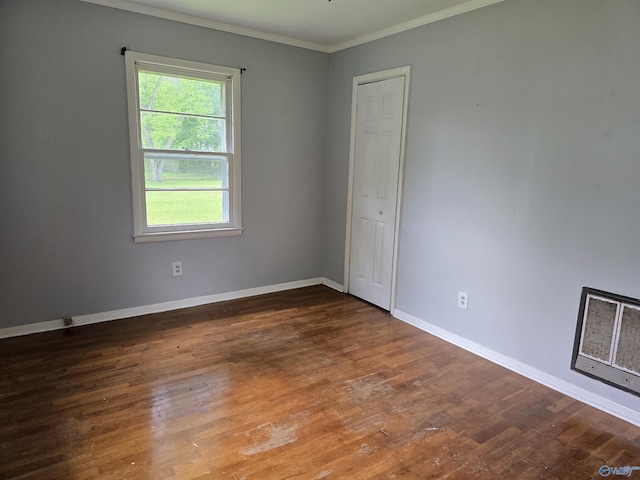 unfurnished room with wood finished floors, ornamental molding, and baseboards