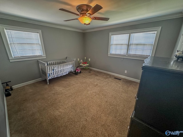 carpeted bedroom with a crib, baseboards, visible vents, and crown molding