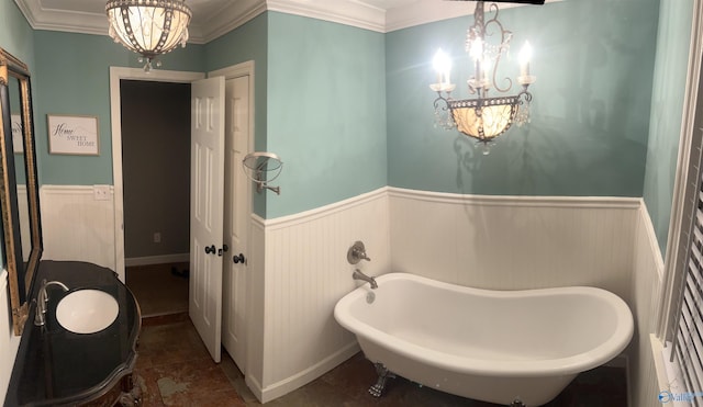 bathroom with a chandelier, ornamental molding, a freestanding bath, and wainscoting