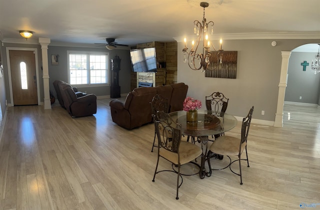 dining space with ornamental molding, arched walkways, light wood-style flooring, and ornate columns