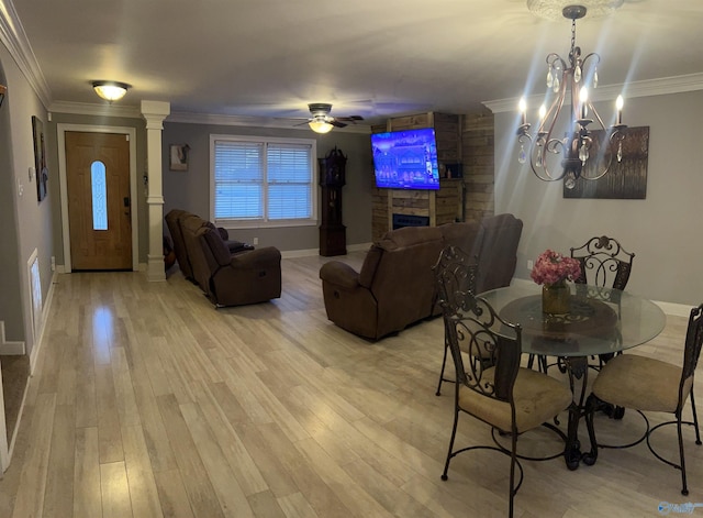 dining area with light wood-style floors, crown molding, a fireplace, and ceiling fan with notable chandelier