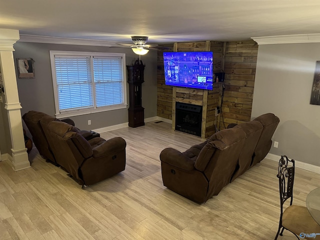 living area with light wood finished floors, decorative columns, crown molding, and a stone fireplace