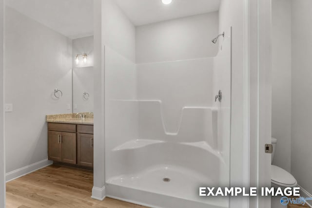 bathroom featuring walk in shower, vanity, wood-type flooring, and toilet