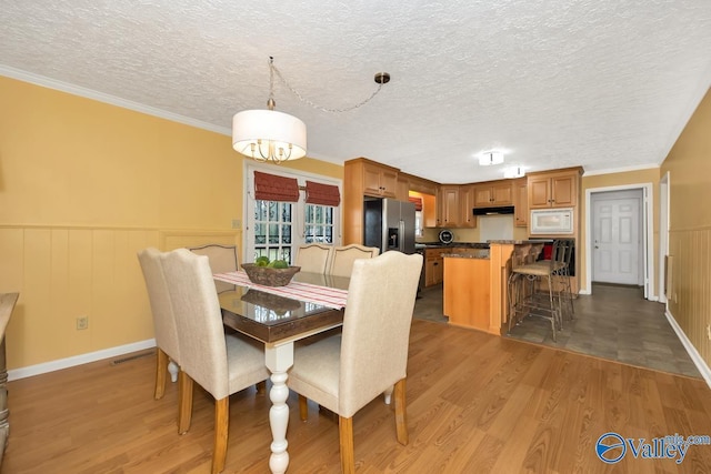 dining space with crown molding, hardwood / wood-style floors, and a textured ceiling