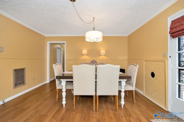 dining room with heating unit, hardwood / wood-style floors, a textured ceiling, and ornamental molding