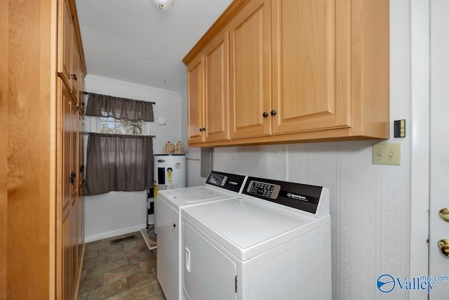 clothes washing area featuring washer and clothes dryer, cabinets, and electric water heater