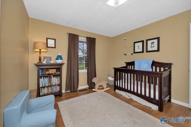 bedroom featuring hardwood / wood-style floors, a crib, and a textured ceiling