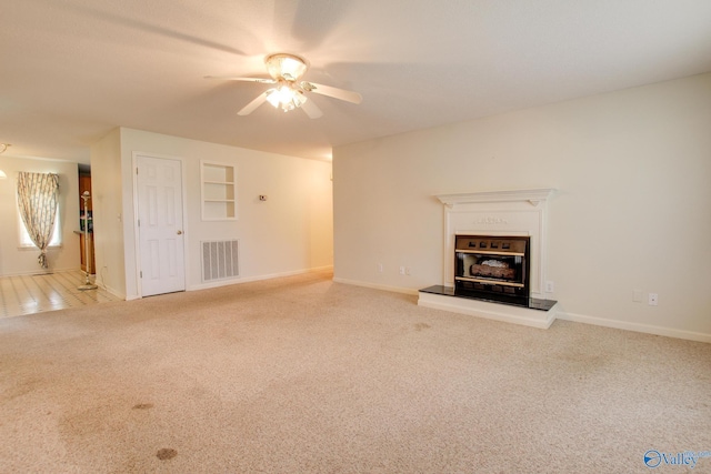20886 Johnson Dr, Athens, AL 35613 - unfurnished living room with carpet floors, visible vents, baseboards, ceiling fan, and a glass covered fireplace