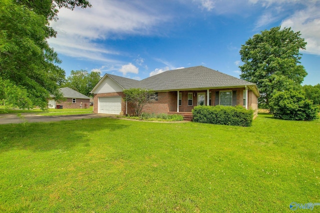 20886 Johnson Dr, Athens, AL 35613 - view of front of home with covered porch, a garage, aphalt driveway, a front yard, and brick siding