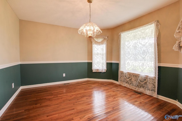 20886 Johnson Dr, Athens, AL 35613 - unfurnished room featuring visible vents, wood finished floors, baseboards, and a notable chandelier