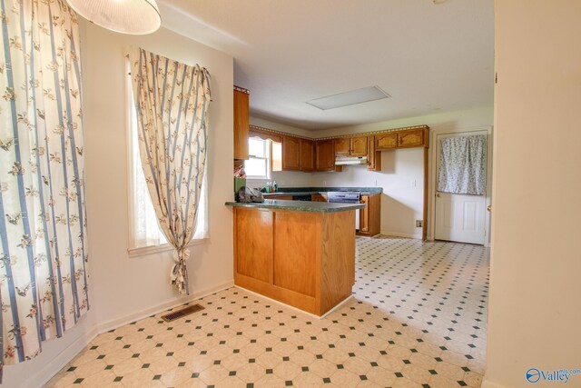20886 Johnson Dr, Athens, AL 35613 - kitchen with a peninsula, brown cabinetry, light floors, visible vents, and dark countertops