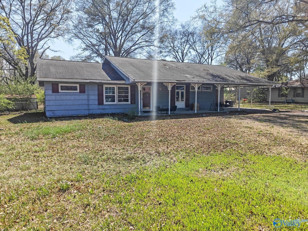 single story home featuring an attached carport, fence, and a front lawn