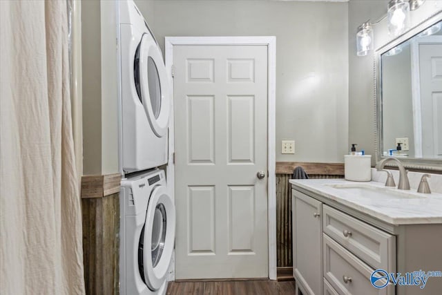 laundry area with stacked washer / dryer, sink, and dark hardwood / wood-style flooring