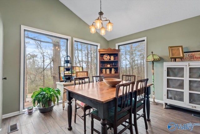 dining space with hardwood / wood-style floors, a notable chandelier, and vaulted ceiling