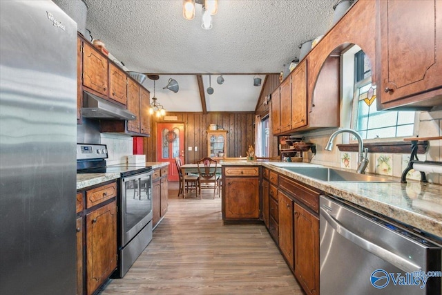 kitchen with sink, decorative light fixtures, a textured ceiling, appliances with stainless steel finishes, and light hardwood / wood-style floors