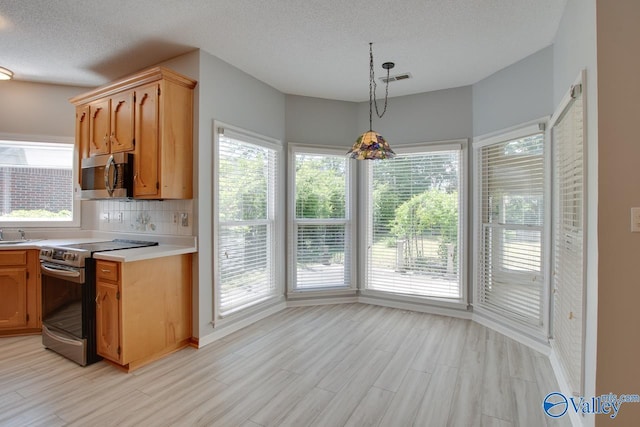 1102 Chesterfield Dr SE, Huntsville, AL 35803 - kitchen featuring stainless steel appliances, light countertops, light wood-style flooring, decorative backsplash, and a textured ceiling