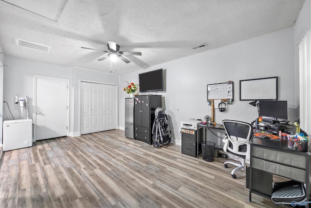 office space featuring visible vents, a ceiling fan, a textured ceiling, and wood finished floors