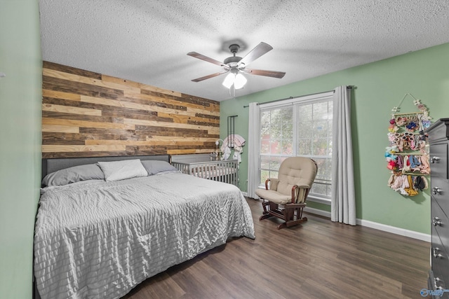 bedroom with wood finished floors, baseboards, ceiling fan, wooden walls, and a textured ceiling