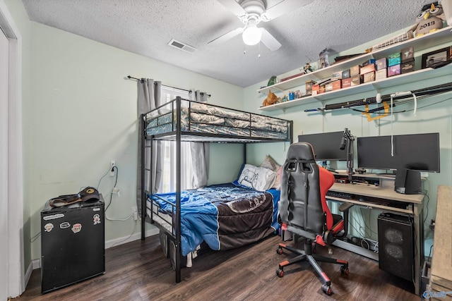 bedroom with a textured ceiling, a ceiling fan, baseboards, wood finished floors, and visible vents