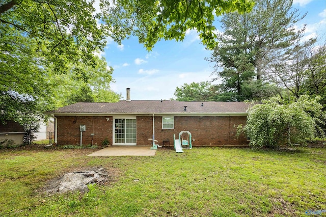 back of property featuring a lawn, a patio, fence, and brick siding