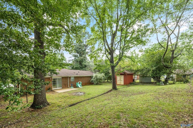 view of yard with an outbuilding, a patio area, fence, and a storage shed