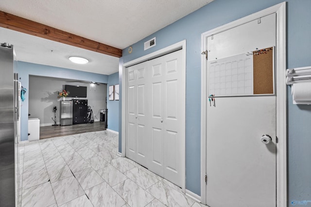 hallway with visible vents, baseboards, marble finish floor, and beam ceiling