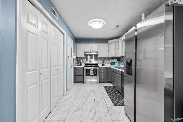 kitchen featuring visible vents, marble finish floor, light countertops, gray cabinets, and stainless steel appliances