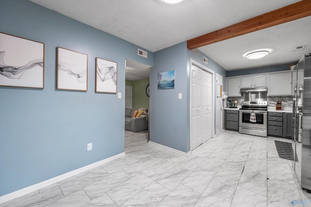 kitchen featuring visible vents, beamed ceiling, light countertops, gray cabinets, and appliances with stainless steel finishes