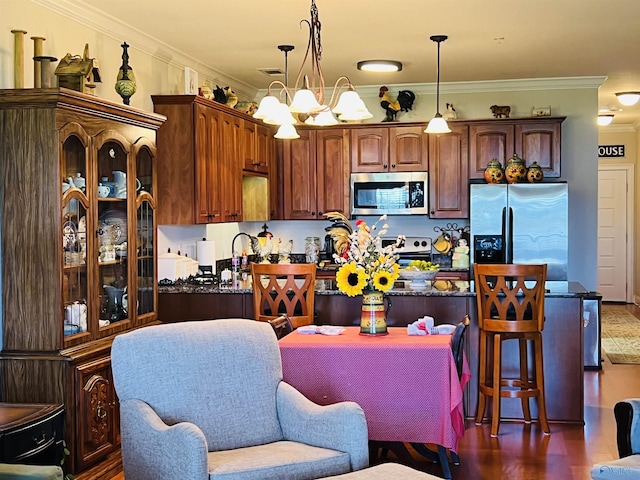 kitchen with ornamental molding, appliances with stainless steel finishes, pendant lighting, and a chandelier