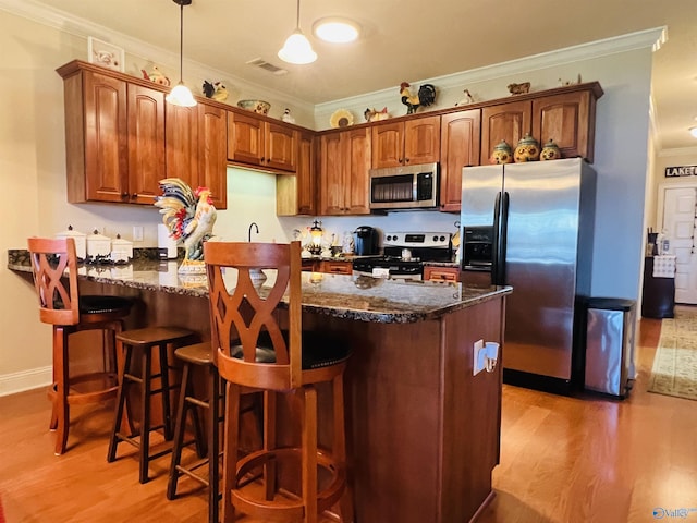 kitchen featuring ornamental molding, appliances with stainless steel finishes, light hardwood / wood-style flooring, and dark stone counters