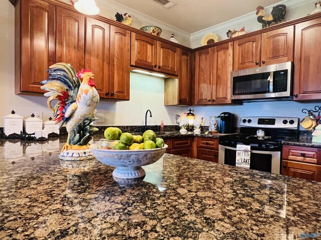 kitchen with dark stone countertops, crown molding, and appliances with stainless steel finishes