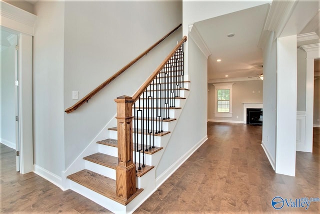 stairs with ornamental molding, hardwood / wood-style floors, and ceiling fan