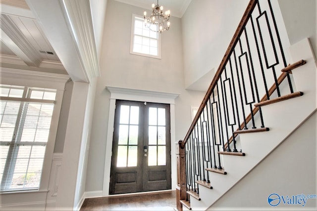 entryway featuring french doors, hardwood / wood-style floors, a chandelier, a high ceiling, and ornamental molding