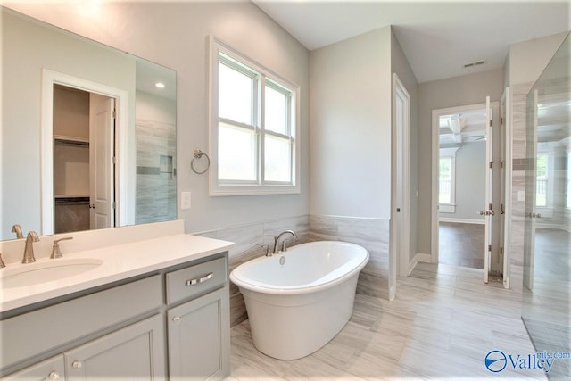 bathroom with vanity, tile walls, a healthy amount of sunlight, and plus walk in shower