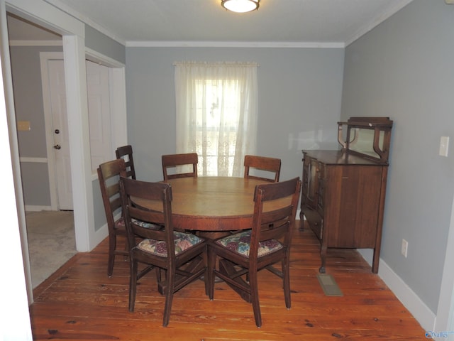 dining area with dark wood-type flooring and ornamental molding