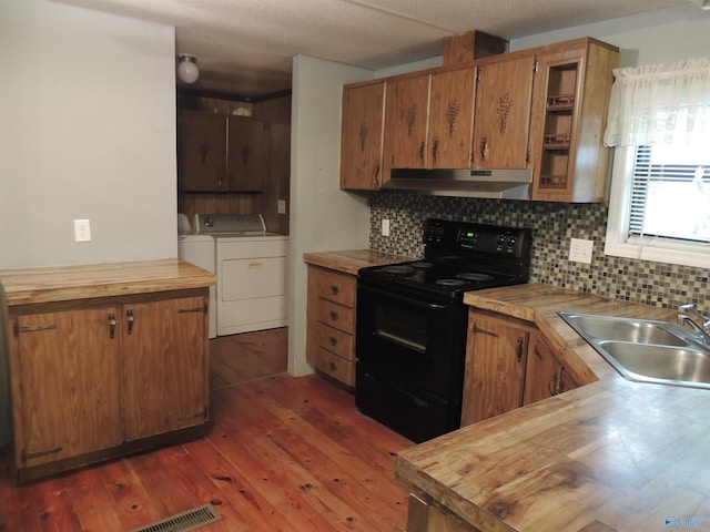 kitchen with sink, black range with electric stovetop, washing machine and clothes dryer, wooden counters, and dark hardwood / wood-style floors