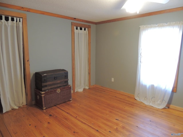 bedroom with ornamental molding, a textured ceiling, and light wood-type flooring