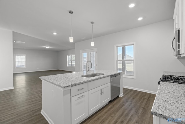 kitchen featuring appliances with stainless steel finishes, pendant lighting, sink, white cabinets, and a center island with sink