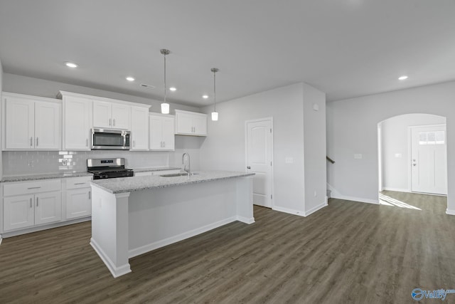 kitchen with white cabinetry, appliances with stainless steel finishes, light stone countertops, and a kitchen island with sink