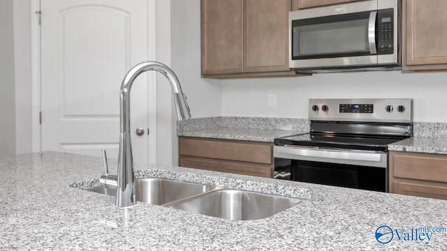 kitchen featuring light stone countertops, sink, and appliances with stainless steel finishes